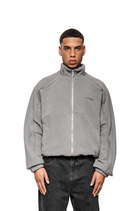 Ein junger Mann trägt die Fleece Jacket Night Owl mit hohem Kragen, elastischen Bündchen und OLA KALA-Logo, kombiniert mit dunklen Jeans.