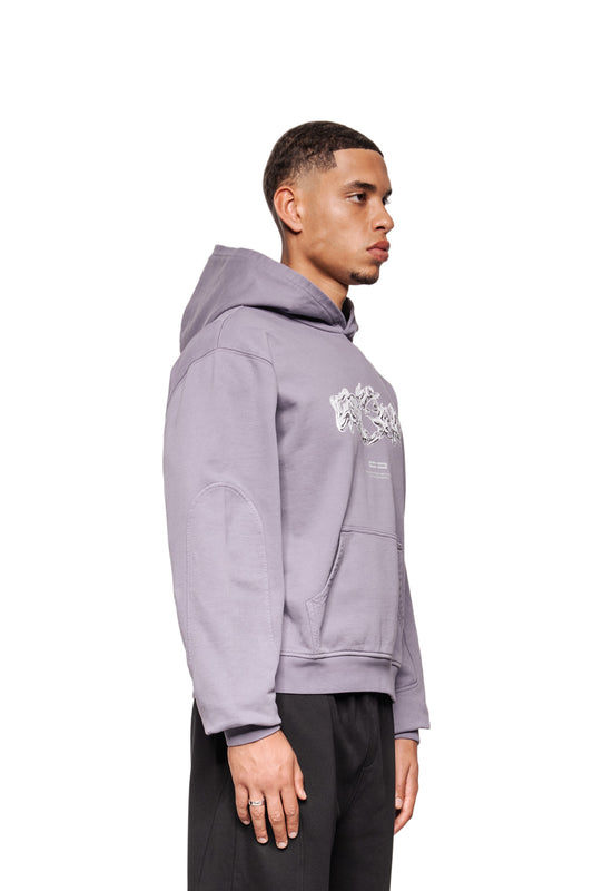 Junger Mann im Profil trägt Greyzone Hoodie Lilac mit Kängurutasche und abstraktem Brustdruck, kombiniert mit schwarzen Hosen.