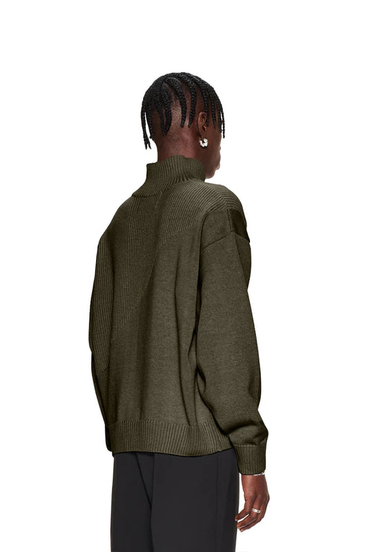 Frau trägt grünen CC Knit Halfzip Khaki Pullover mit verschiedenen Strickmustern, überschnittenen Schultern und versetztem Saum, passend zur OLAKALA Oversized Unisex-Kollektion.