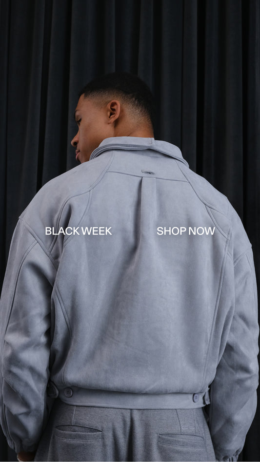 Rückenansicht eines Mannes in einer hellgrauen, oversized Jacke mit Taillengürtel; dunkler Hintergrund, Textüberlagerung „BLACK WEEK“ und „SHOP NOW“.