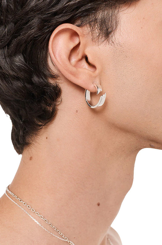 Silberner Synergy Destroyed Ohrring am Ohr einer Person, im charakteristischen „zerstörtem“ Look, präsentiert im offiziellen OLAKALA® Onlineshop.