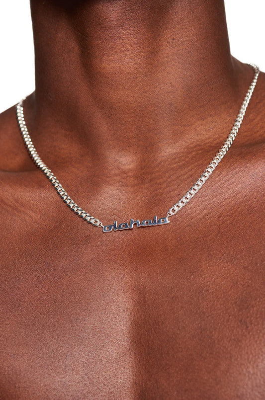 Person wearing CC Logo Chain, silver-plated with OLA KALA pendant, 0.5 cm wide Cuban Link chain, 50 cm long, modern jewelry by OLAKALA.
