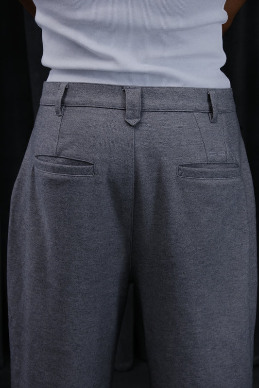 Graue Stoffhose mit Gürtelschlaufen, zwei hintere Paspeltaschen und glatter Textur – Nahaufnahme vom Bund.