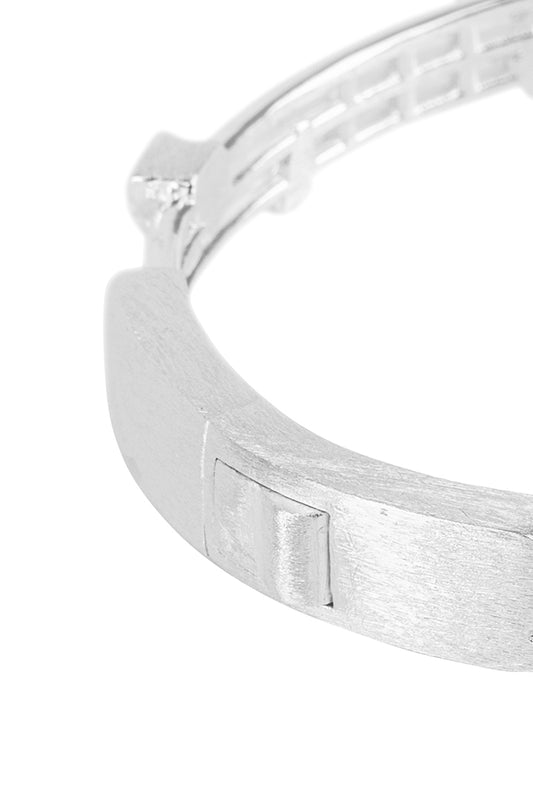 Close-up of a silver-plated brushed cuff bangle with engraved OLA KALA logo in 