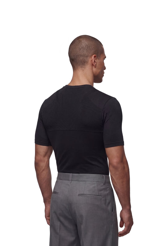 Mann von hinten in einem OLAKALA Compression T-Shirt Black mit strukturiertem Rückenpanel, betont die körpernahe, nahtlose Passform für optimale Bewegungsfreiheit.