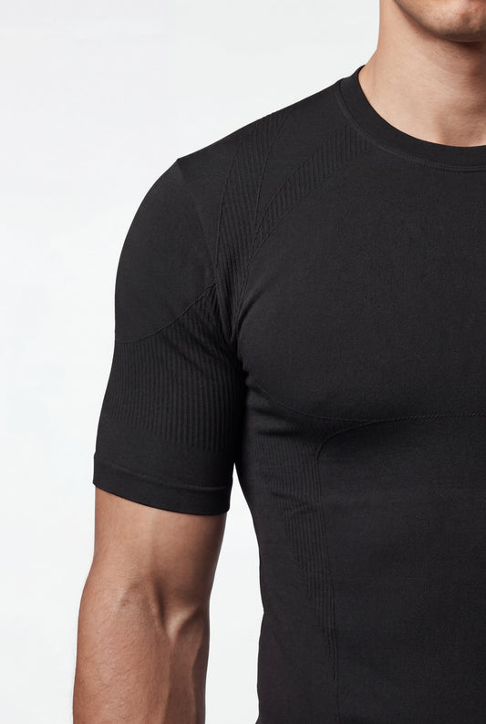 Ein Mann trägt ein eng anliegendes, schwarzes Compression T-Shirt Black von OLAKALA mit nahtloser Konstruktion und anatomischen Strickmustern für optimale Passform und Bewegungsfreiheit.