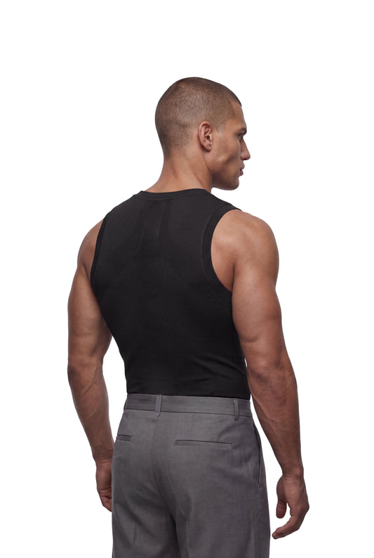 Männliches Model von hinten in schwarzem Compression Tanktop Black, das nahtlose Passform und hohe Bewegungsfreiheit bietet, kombiniert mit grauen Hosen.