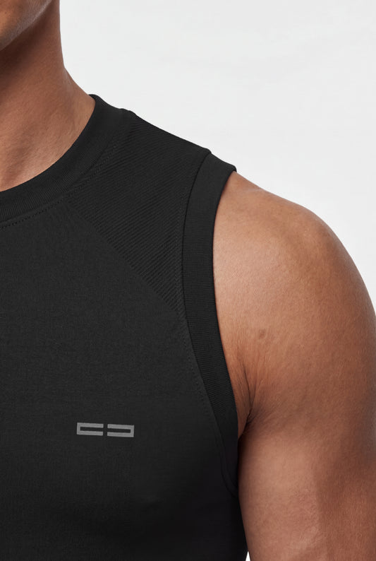 Person mit schwarzem OLAKALA Compression Tanktop, nahtlose Passform, eingestrickte Zonen für Funktionalität, leichtes Rippenmuster an Schultern und Armloch.