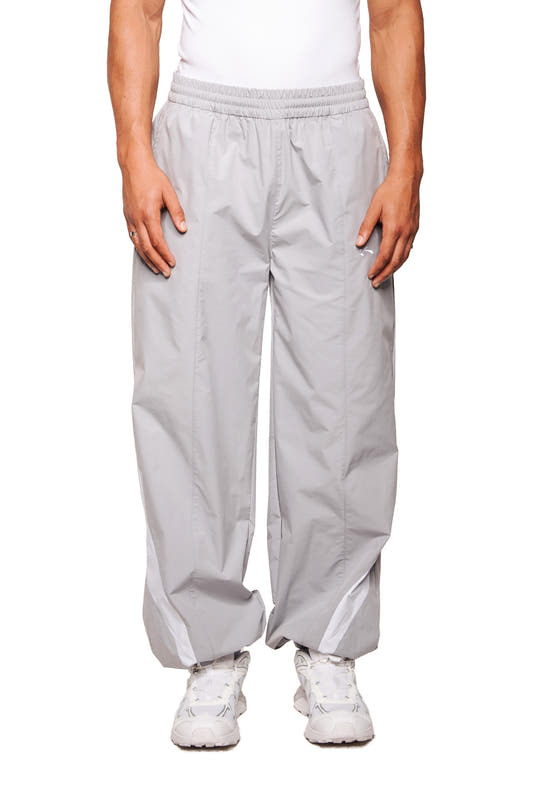 Person trägt die Sports Trackpants Gray aus robustem Rip-Stop-Gewebe mit elastischem Bund; zeigt gesticktes OLAKALA Sports Logo am linken Bein.