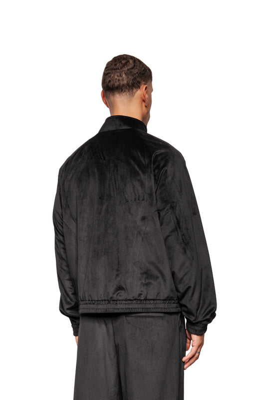 Person from behind in the Sports Velour Jacket Black with dividing seams, stand-up collar, elasticated cuffs and loose fit, wears matching pants, emphasizes sporty-modern look.