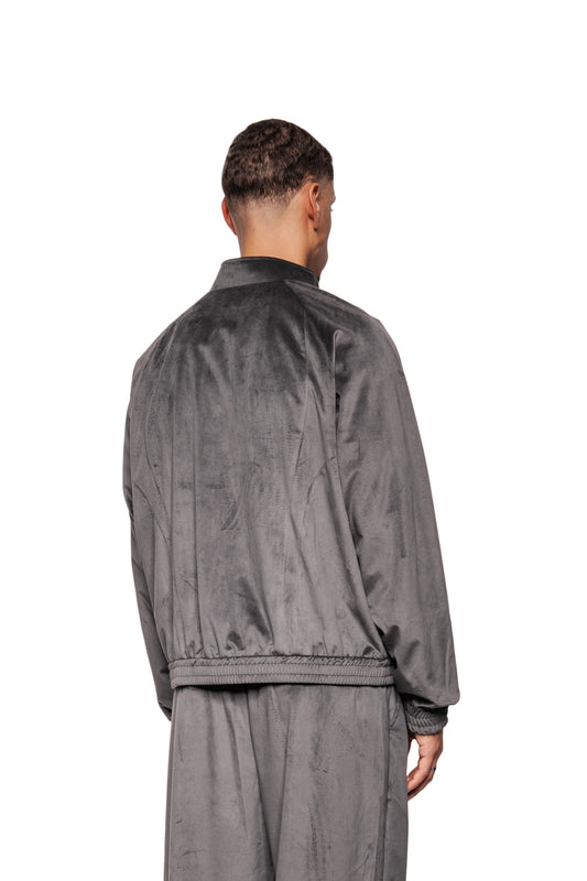 Mann in grauer Sports Velour Jacke mit Raglanärmeln und elastischem Bund, zeigt Rückansicht. Lockere Passform, weiches Velours, sportlich-modern.