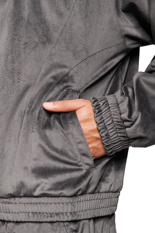 Hand in Seitentasche einer grauen Sports Velour Jacke mit elastischen Bündchen, samtigem Stoff und sportlich-modernen Teilungsnähten für optimalen Tragekomfort.