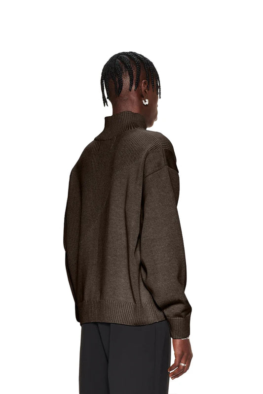 Frau trägt CC Knit Halfzip Braun, einen oversized Strickpullover mit verschiedenen Mustern, überschnittenen Schultern und versetztem Saum, passend für Unisex.