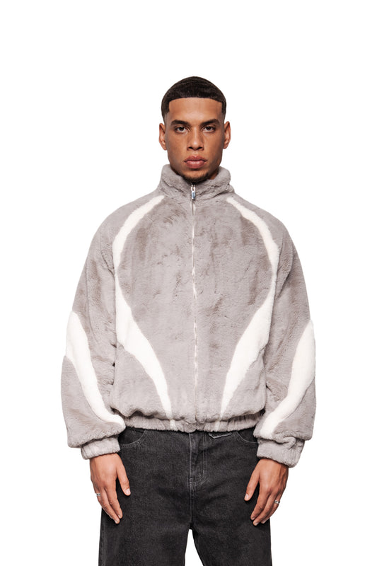 Männliches Model in grauer Two-Toned Fur Jacket mit Stehkragen, weißen Einsätzen, Reißverschluss und elastischen Bündchen, passend zu dunklen Hosen.