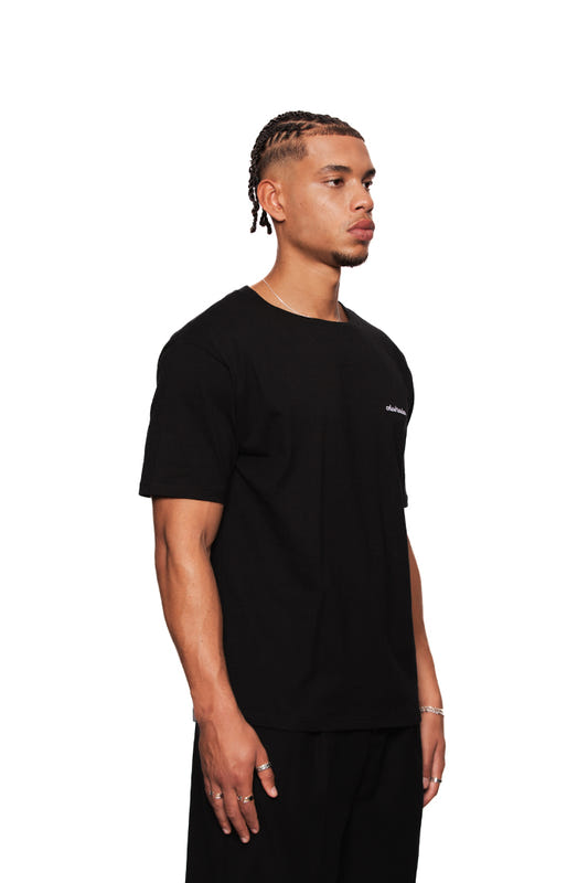 NC T-Shirt Black Regular, unisex, mit OLA KALA Nachbarschafts-Kirschen-Grafik auf dem Rücken und schwarzem gesticktem Logo auf der linken Brust, hergestellt in der EU.