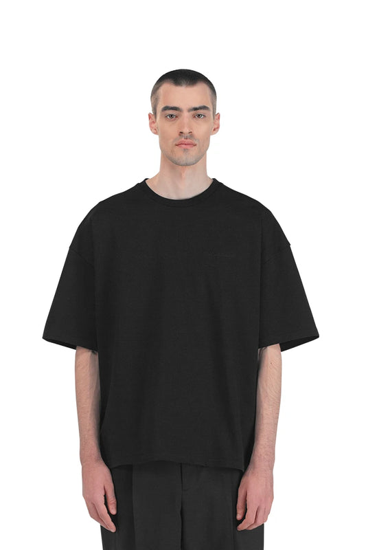 Man wearing a black CC T-shirt with embroidered OLA KALA logo on the chest, oversized unisex design, part of the Core Collection by OLAKALA.