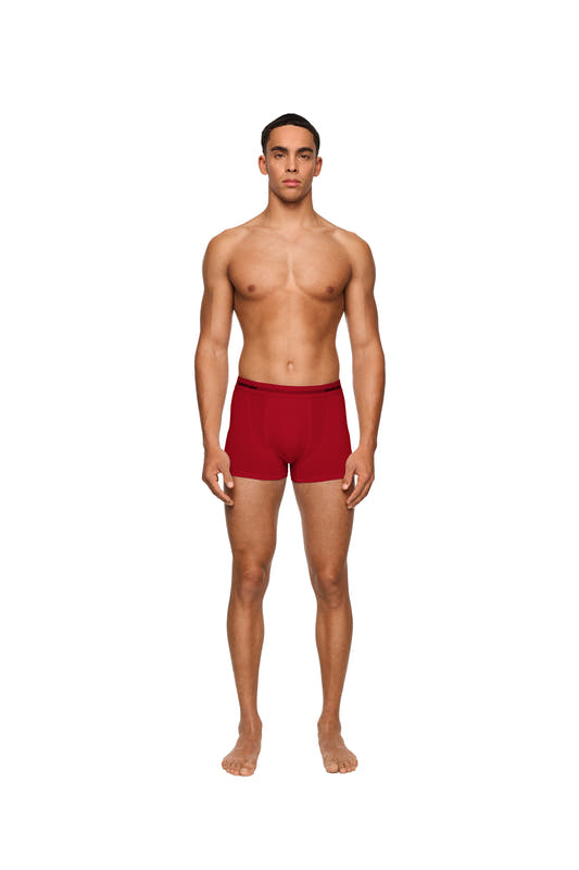 A man wears OLAKALA boxer shorts in a 3-pack with elastic waistband and woven logo, presented in a red gift box.
